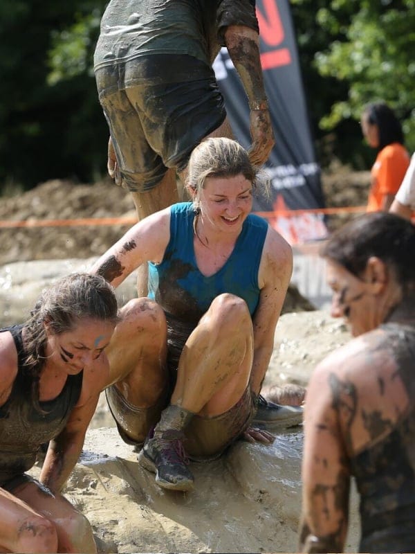 Sarah crouched and covered in mud.